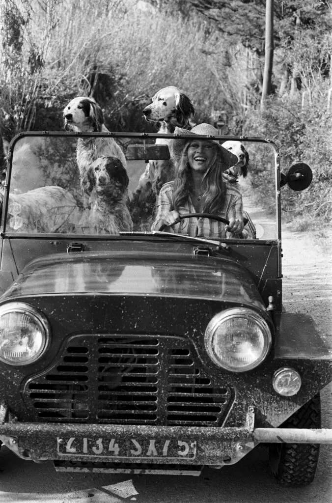 A woman and her dogs in an early Moke, in black and white