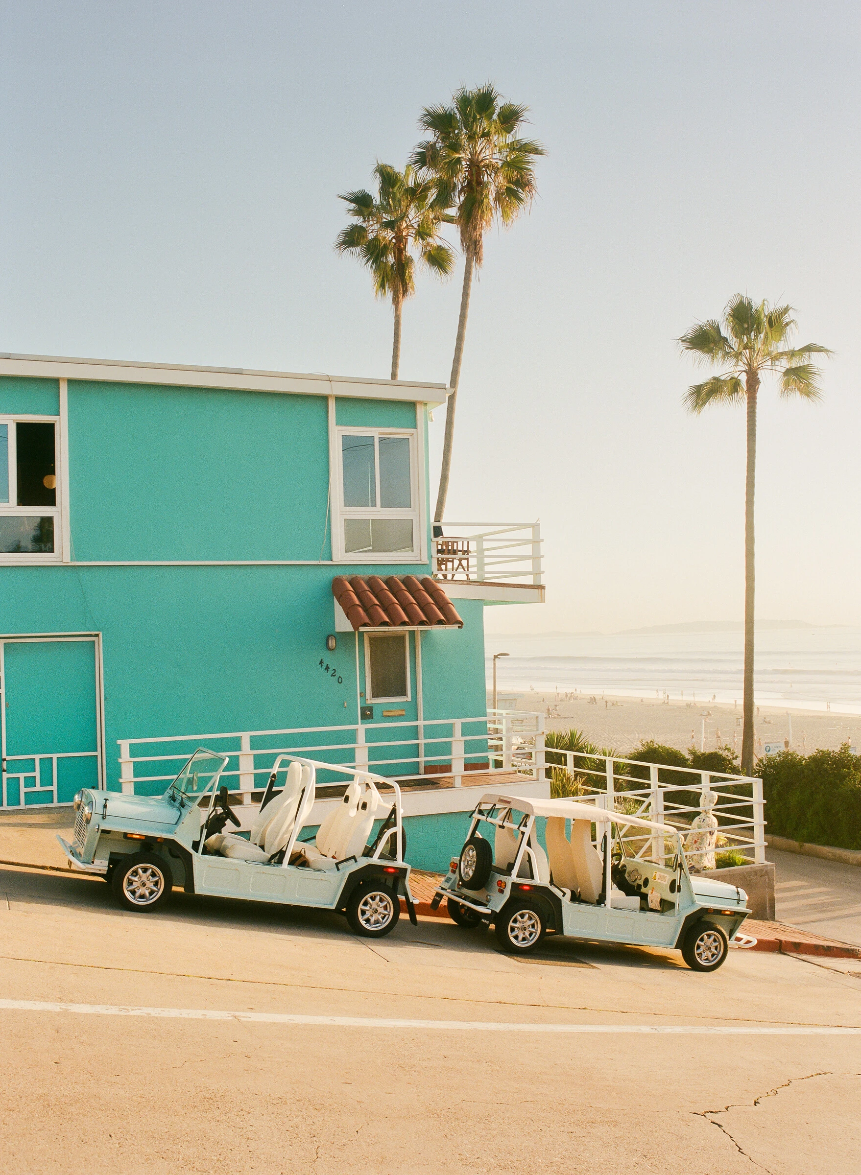 Electric Moke parked on a palm-lined street